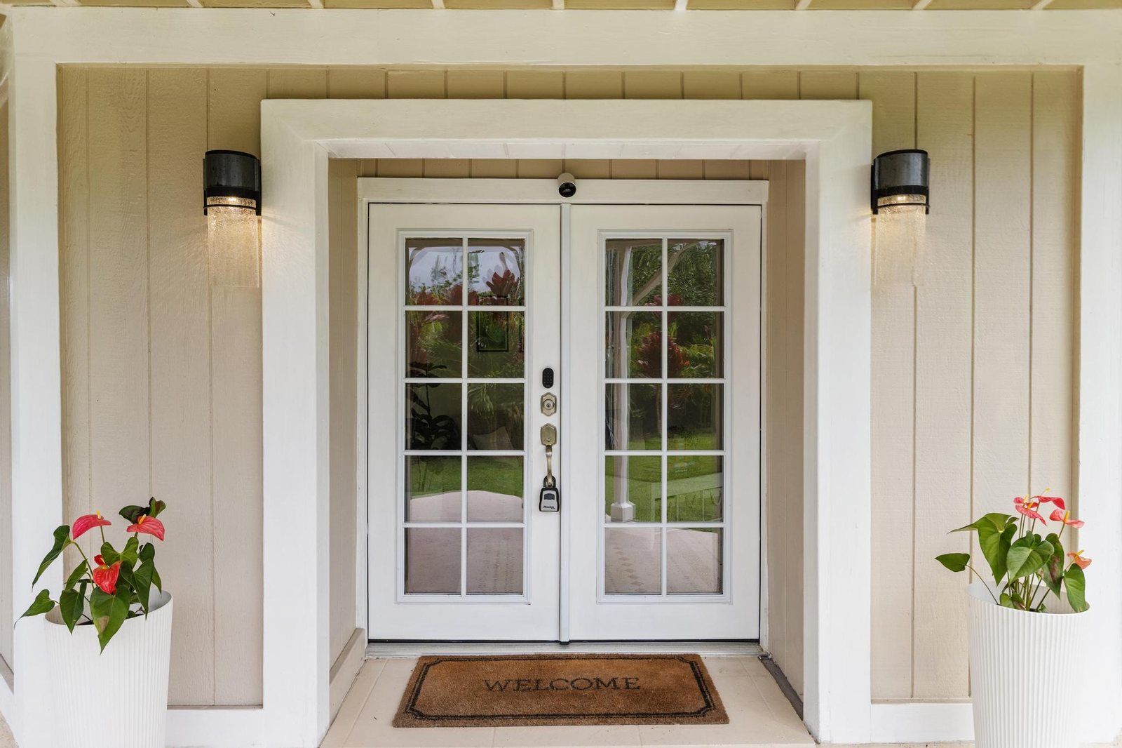 Glass-paned entry doors flanked by anthuriums