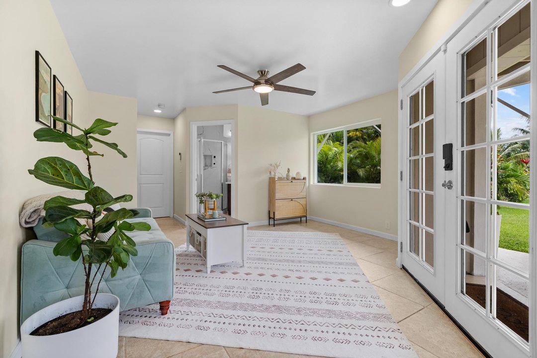 Garden-level living room with French doors open to the covered lanai and garden