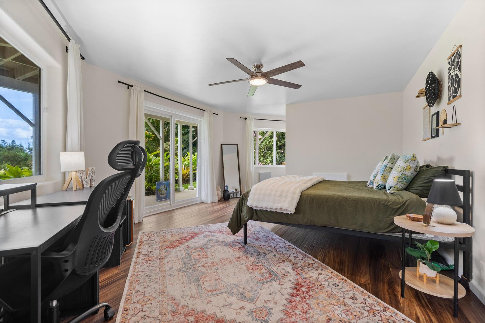 Garden-level bedroom arranged with a bed and a work desk beside sliding doors to the garden