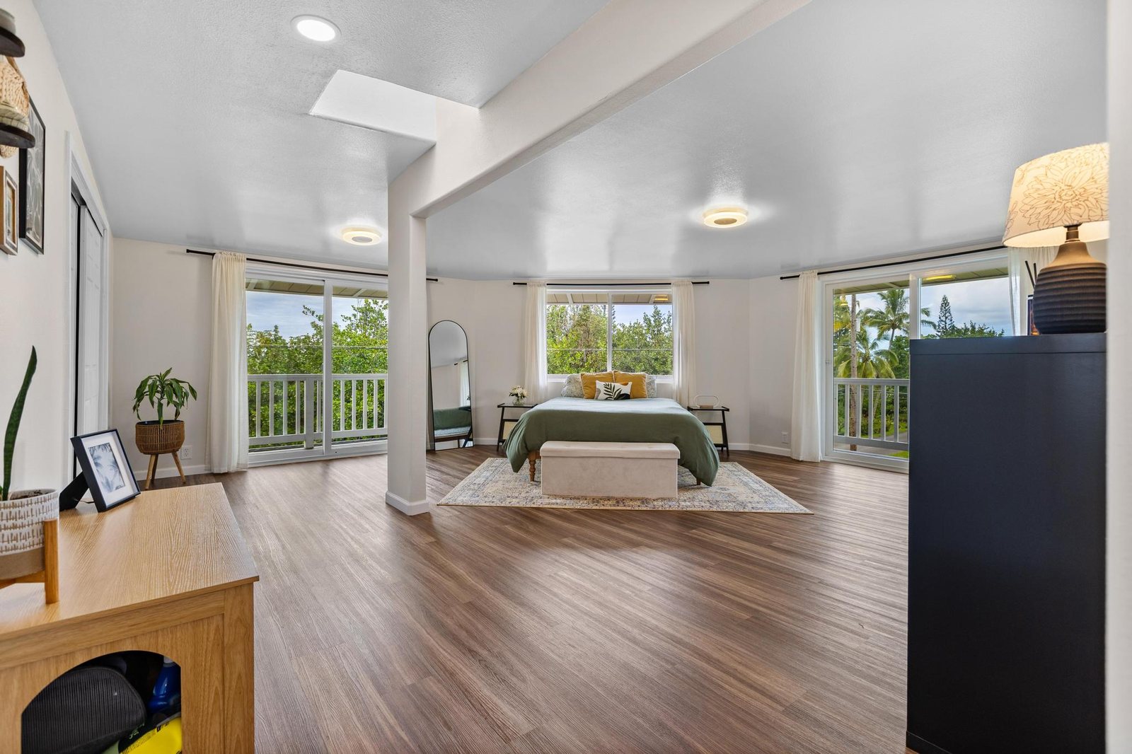 Top-floor primary bedroom wrapped in windows, with sliding doors to its lanai