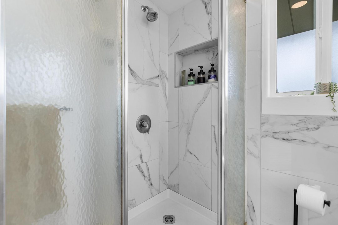Glass-enclosed shower with marble-look tile