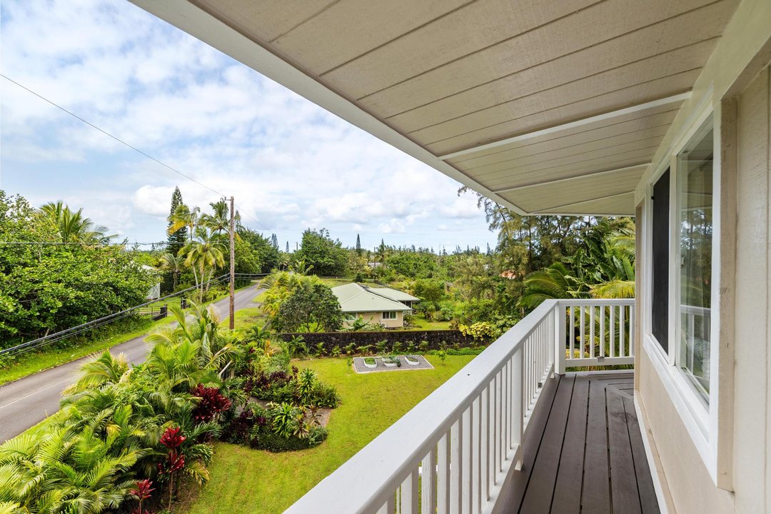 The top-floor lanai off the primary suite, looking over the front lawn and grounds