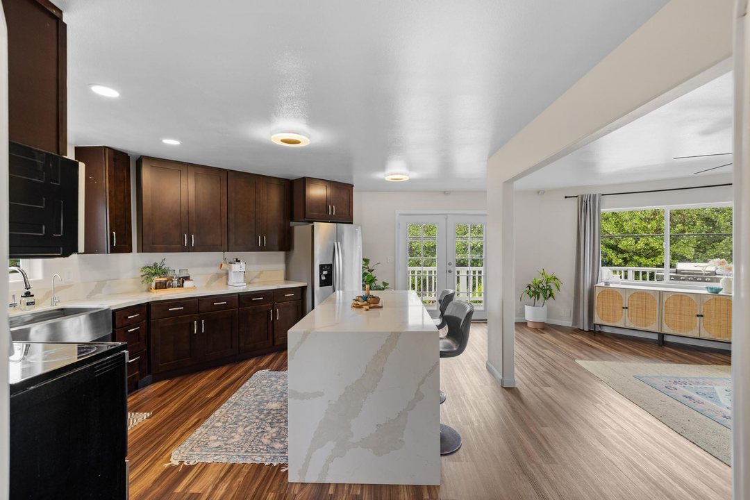 Renovated kitchen with dark shaker cabinets, a waterfall quartz island and French doors to the lanai