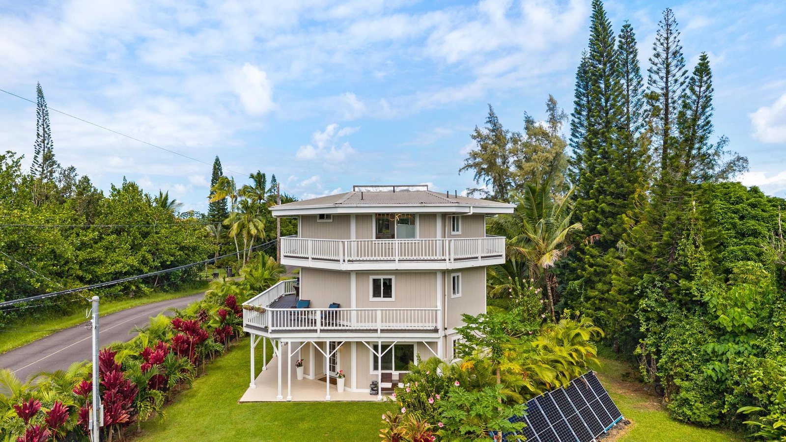 Elevated view of the octagonal three-level home with stacked lanais, red ti and tall pines