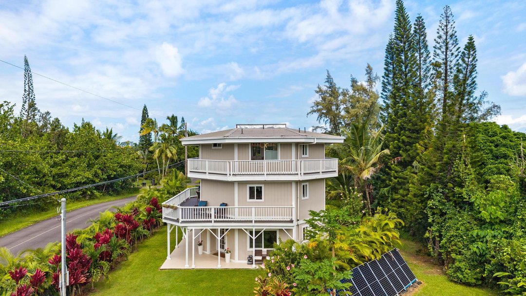 Elevated view of the octagonal three-level home with stacked lanais, red ti and tall pines